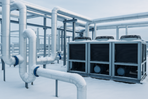 Industrial HVAC system in winter with insulated pipes and chillers, illustrating glycol freeze protection for closed loop systems.
