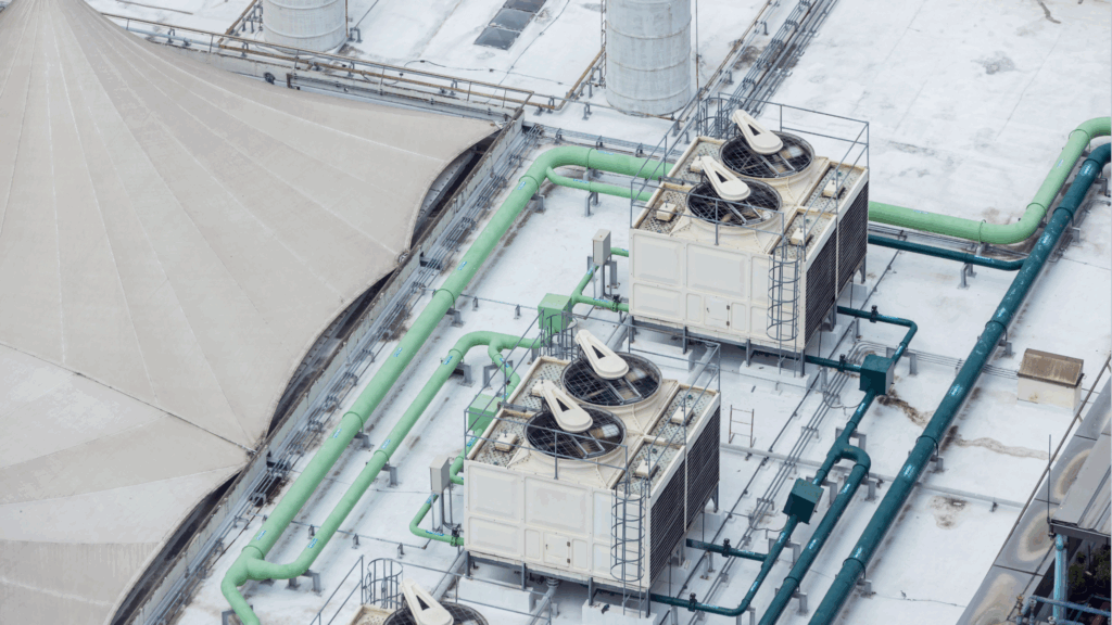 Cooling towers and rooftop mechanical systems connected by industrial piping on a university facility.